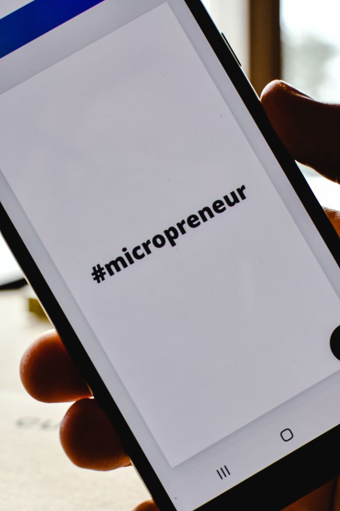 creative Close-up of a hand holding a smartphone with the hashtag #micropreneur on screen, symbolizing entrepreneurship.